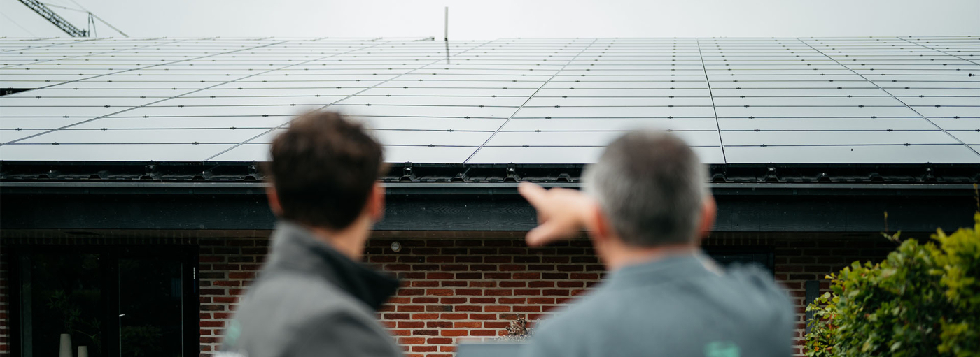 Onze installateurs kijken naar zonnepanelen op een dak; illustratie van dalende opbrengst en maatregelen om die te verbeteren.